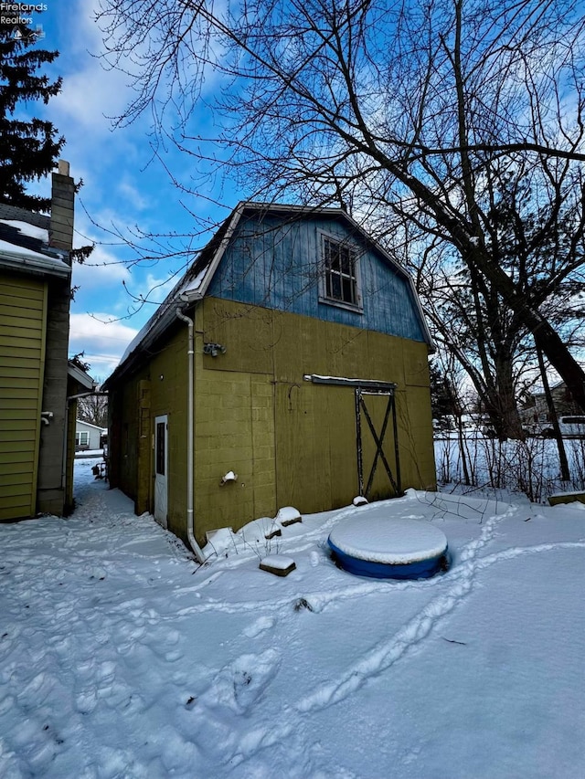 snow covered structure featuring an outbuilding and a barn