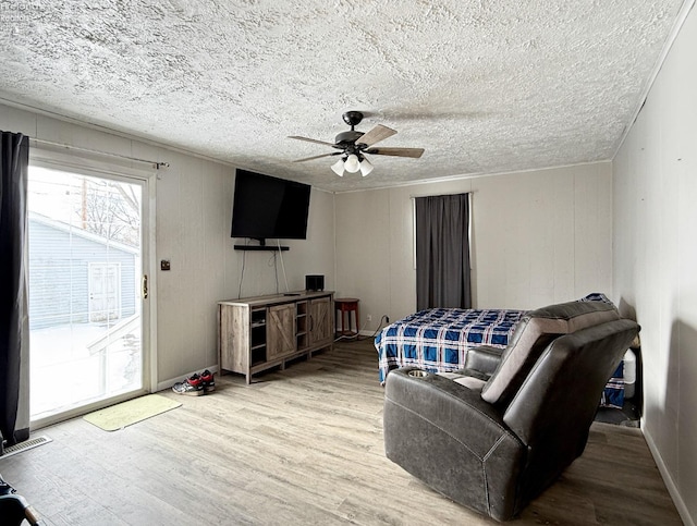 living area with a textured ceiling, ceiling fan, wood finished floors, and visible vents