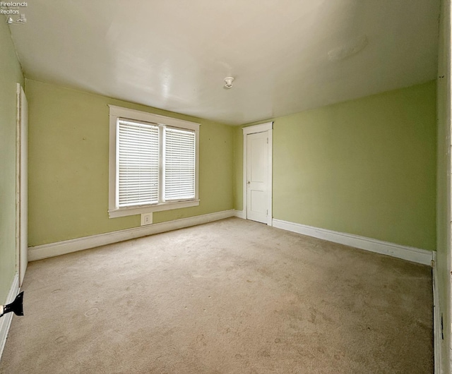 unfurnished room with light carpet and baseboards