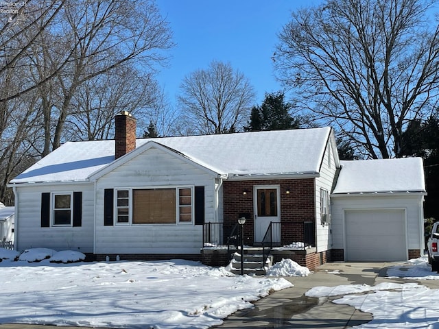 view of front of property featuring an attached garage, a chimney, and brick siding