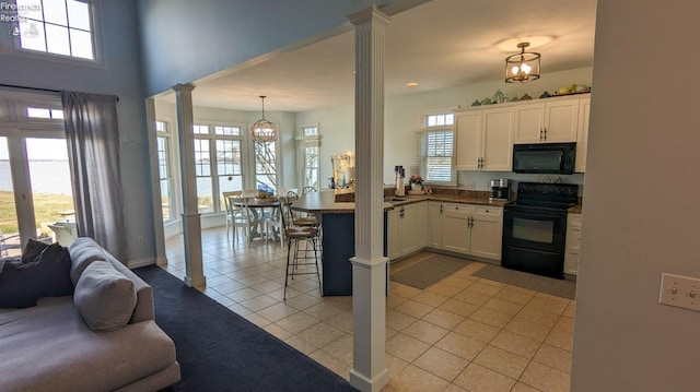 kitchen featuring pendant lighting, white cabinets, open floor plan, black appliances, and ornate columns