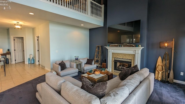 tiled living area featuring recessed lighting, a high ceiling, a fireplace, and baseboards