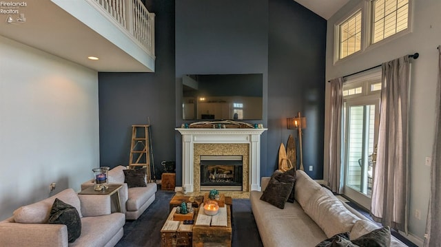 living room featuring dark wood-style floors, a fireplace, and a towering ceiling