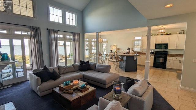 living area with light tile patterned floors, decorative columns, a water view, high vaulted ceiling, and recessed lighting