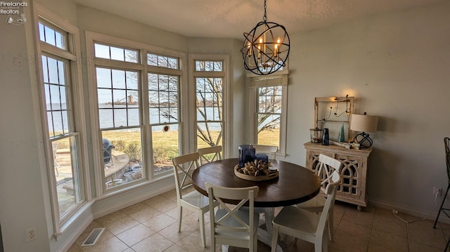 tiled dining room featuring a chandelier, a water view, visible vents, and baseboards