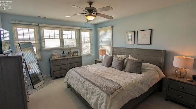 bedroom featuring a ceiling fan, light colored carpet, visible vents, and multiple windows