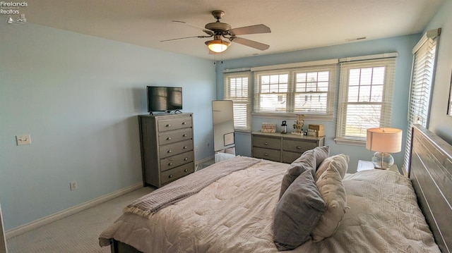 bedroom featuring light carpet, visible vents, multiple windows, and baseboards