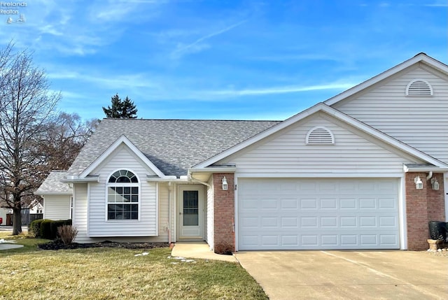 ranch-style home featuring roof with shingles, brick siding, a front lawn, and an attached garage