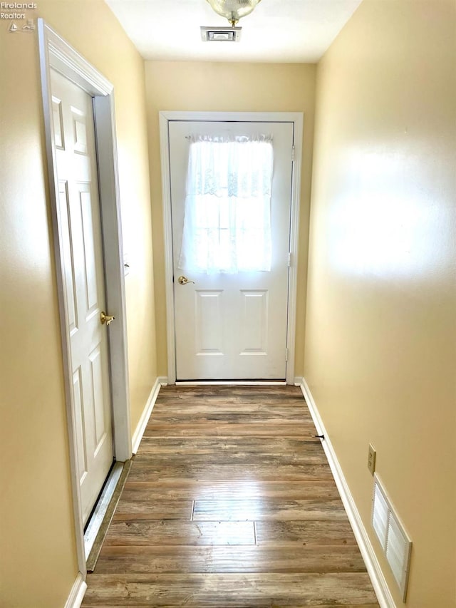 doorway featuring dark wood-type flooring, visible vents, and baseboards