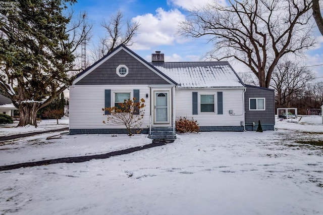 view of front of house featuring entry steps, metal roof, and a chimney