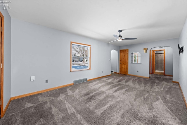 unfurnished room with plenty of natural light, visible vents, arched walkways, and carpet flooring