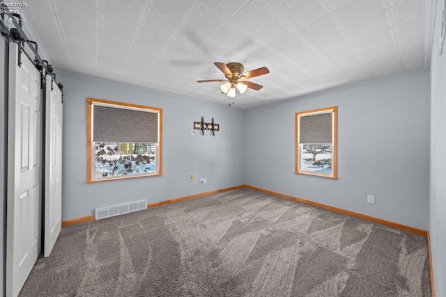 spare room with a healthy amount of sunlight, baseboards, visible vents, and dark carpet