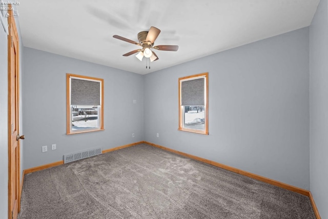 spare room with carpet floors, visible vents, and baseboards