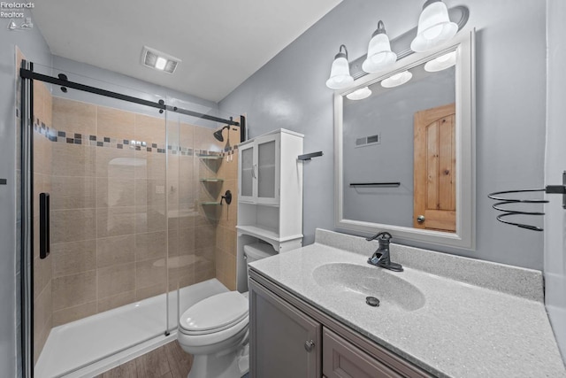 full bathroom with toilet, wood finished floors, vanity, visible vents, and a shower stall