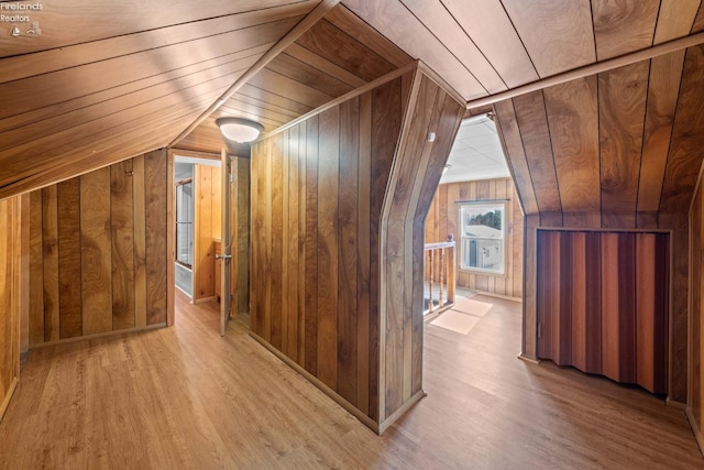 additional living space with lofted ceiling, light wood-type flooring, wood ceiling, and wooden walls