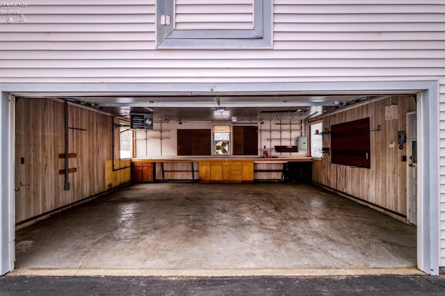 garage featuring a workshop area, electric panel, and wooden walls