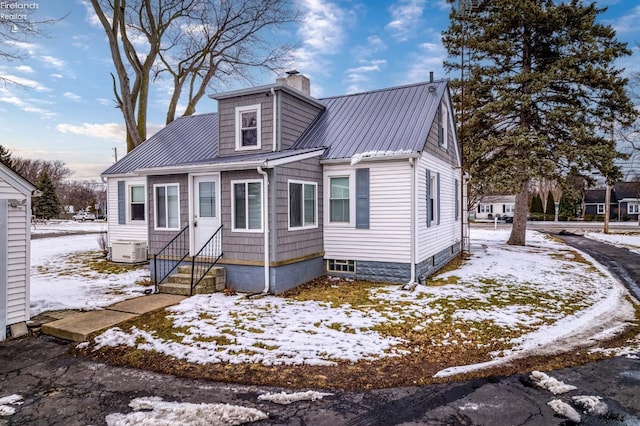 bungalow-style home with entry steps, metal roof, and a chimney