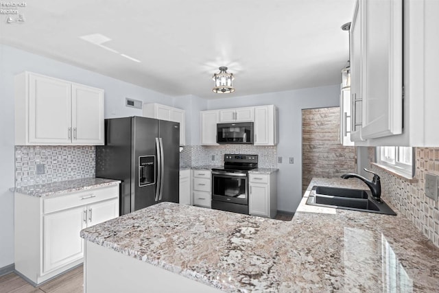 kitchen featuring black microwave, stainless steel fridge, white cabinetry, a sink, and range with electric stovetop