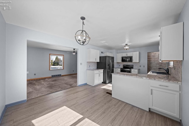 kitchen with light wood-style flooring, a sink, white cabinetry, backsplash, and black appliances