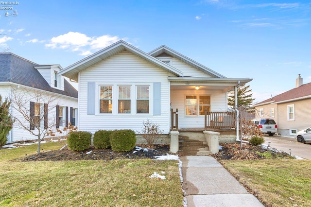 bungalow featuring a porch and a front lawn