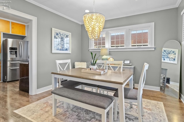 dining room featuring a notable chandelier, baseboards, wood finished floors, and crown molding