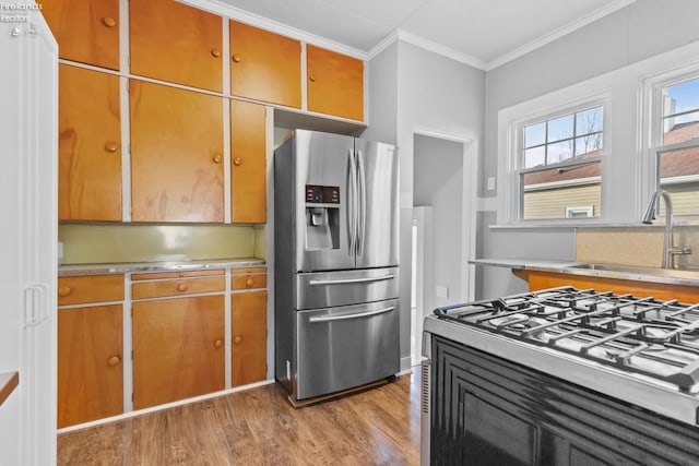 kitchen featuring a sink, light countertops, ornamental molding, light wood-type flooring, and stainless steel refrigerator with ice dispenser