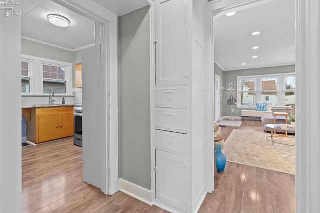 corridor with light wood-style flooring, baseboards, crown molding, and recessed lighting