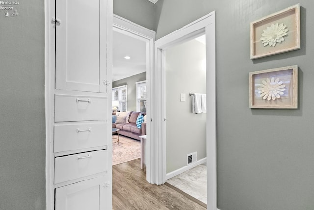 corridor with visible vents, baseboards, and wood finished floors