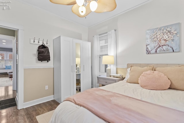 bedroom featuring a ceiling fan, crown molding, baseboards, and dark wood-style flooring