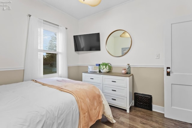 bedroom featuring baseboards, ornamental molding, and wood finished floors