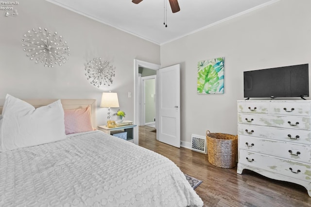 bedroom with ceiling fan, wood finished floors, visible vents, baseboards, and crown molding