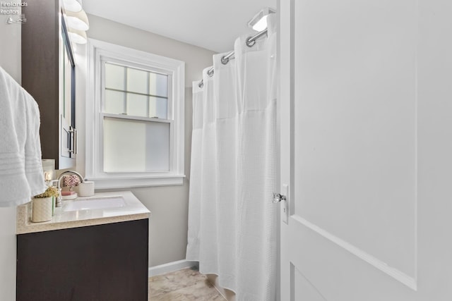 bathroom featuring curtained shower, vanity, and baseboards