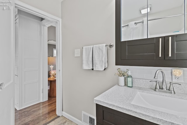 bathroom featuring vanity, wood finished floors, visible vents, and baseboards