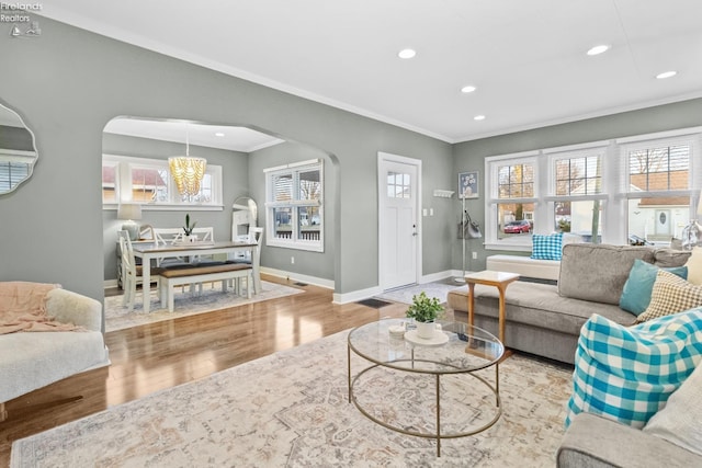 living room with baseboards, arched walkways, wood finished floors, crown molding, and recessed lighting