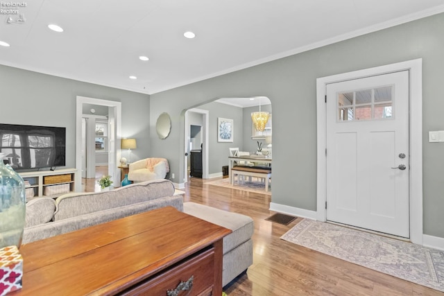 living room with baseboards, arched walkways, wood finished floors, and ornamental molding