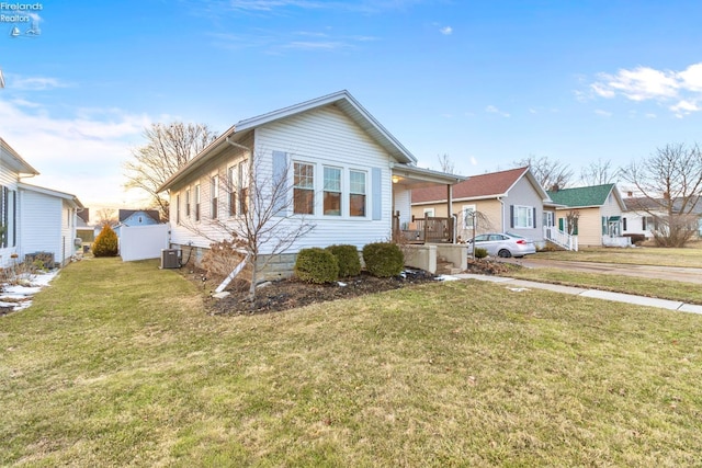 bungalow-style home with a front lawn, a residential view, and central air condition unit