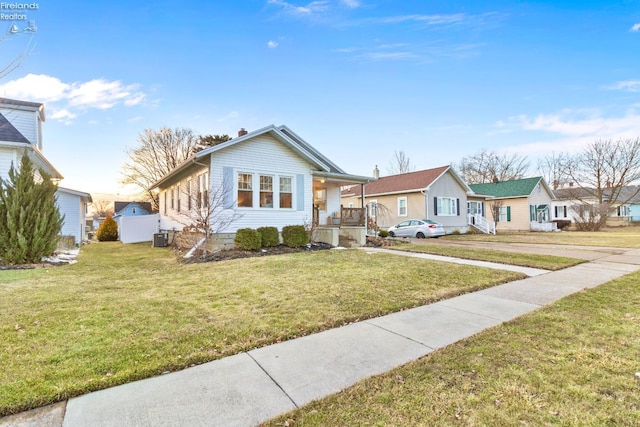 bungalow featuring covered porch, a chimney, central AC unit, and a front yard