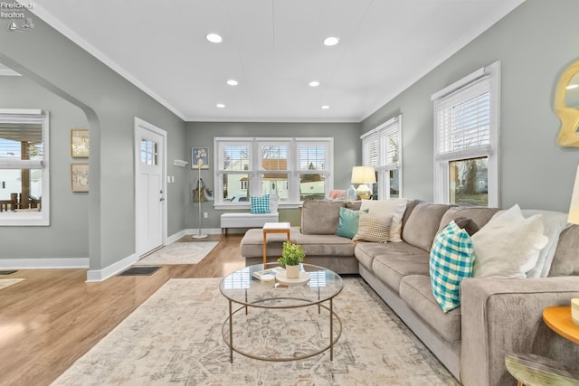 living room with arched walkways, crown molding, recessed lighting, visible vents, and wood finished floors