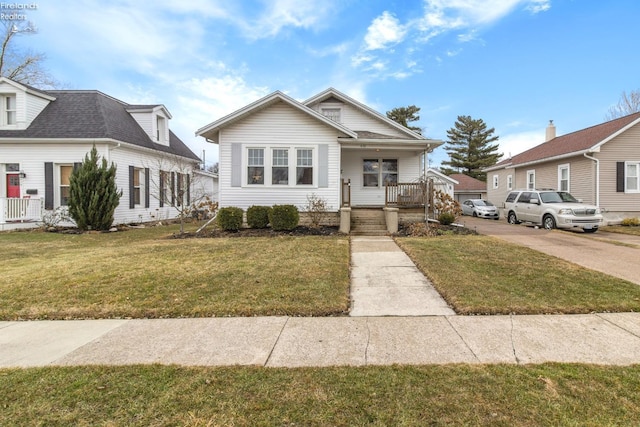 bungalow-style house with covered porch, concrete driveway, and a front lawn