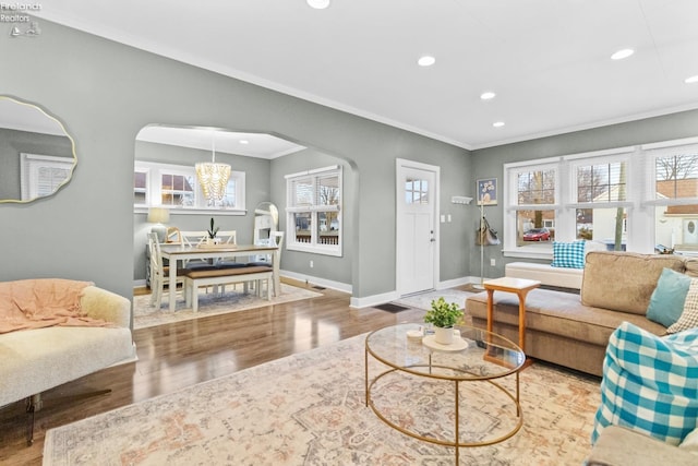 living room featuring arched walkways, recessed lighting, wood finished floors, baseboards, and ornamental molding