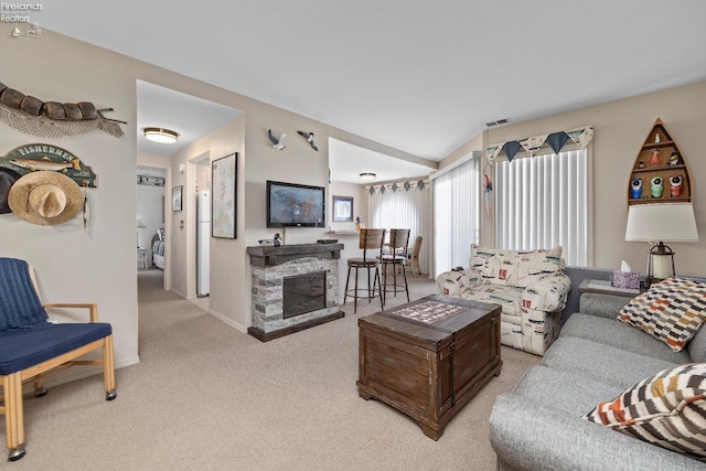 living room featuring baseboards, visible vents, light colored carpet, vaulted ceiling, and a fireplace