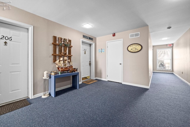 entryway with visible vents, dark carpet, and baseboards