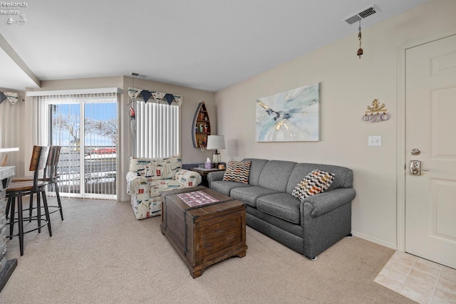 living room with light tile patterned floors, visible vents, and light colored carpet