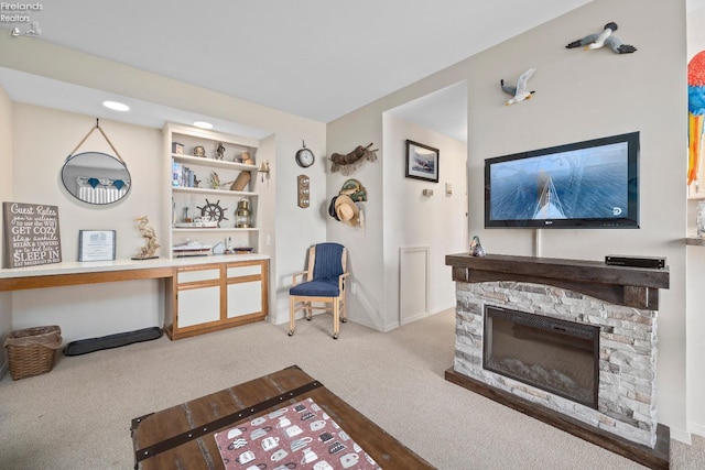 carpeted living area with a stone fireplace and baseboards