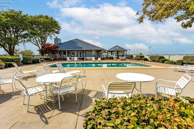 pool with a gazebo, fence, and a patio