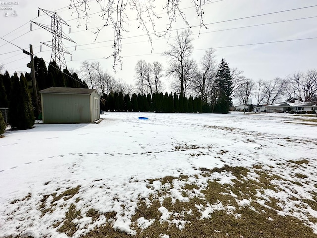 snowy yard featuring a garage, an outdoor structure, and a shed