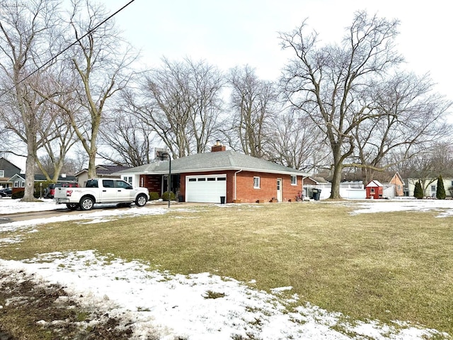 exterior space featuring a garage, a yard, a chimney, and brick siding