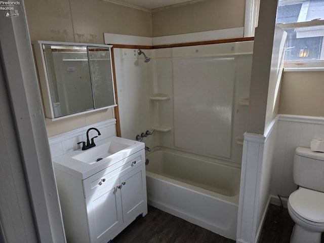 full bathroom with toilet, a wainscoted wall, wood finished floors, vanity, and  shower combination