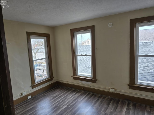 empty room with dark wood-style floors, a healthy amount of sunlight, and a textured ceiling