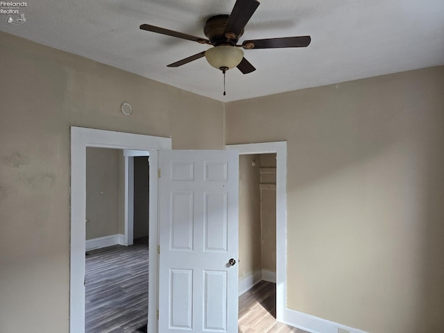 unfurnished bedroom with ceiling fan, baseboards, and wood finished floors